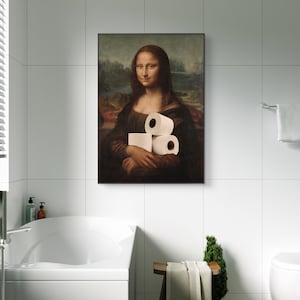 May include: A framed print of the Mona Lisa holding three rolls of toilet paper. The artwork is displayed in a modern bathroom setting with white tile walls and a white bathtub.