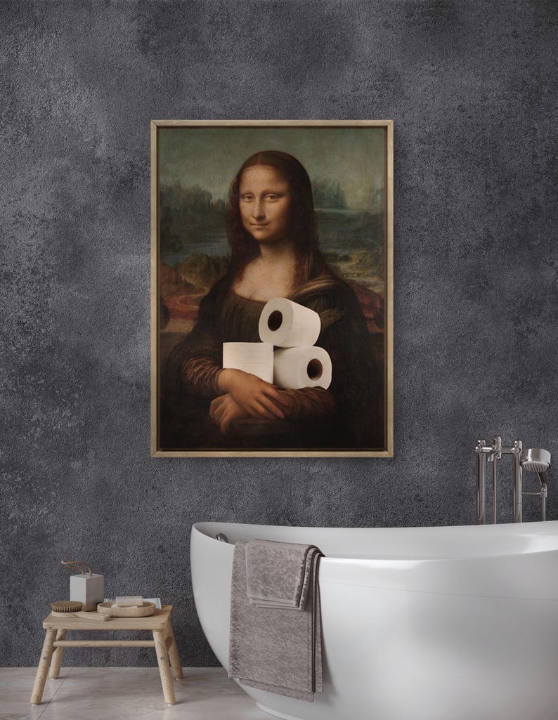 May include: Framed print of the Mona Lisa holding rolls of toilet paper. The artwork is in a wooden frame and hangs on a dark gray wall. The bathroom setting includes a white bathtub and a small wooden stool.