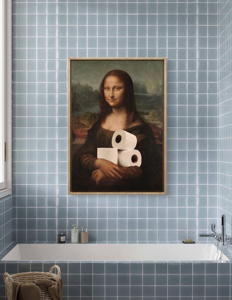 May include: Framed artwork of the Mona Lisa holding rolls of toilet paper, a humorous take on the classic painting. The artwork is displayed in a bathroom with blue tiled walls and a white bathtub.