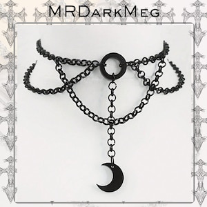 May include: Black choker necklace featuring a crescent moon pendant. The necklace is made of linked chains and a circular centerpiece. The text "MRDARKMEG" is at the top of the image.
