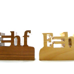 May include: Two wooden blocks spelling out the word "Ehf" in all caps. The block on the left is a darker brown wood, while the block on the right is a lighter, natural wood.