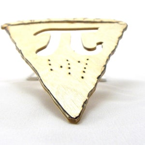 May include: A wooden pie-shaped ornament with a cutout of the mathematical symbol pi. The ornament is light brown and has a rough, rustic texture.