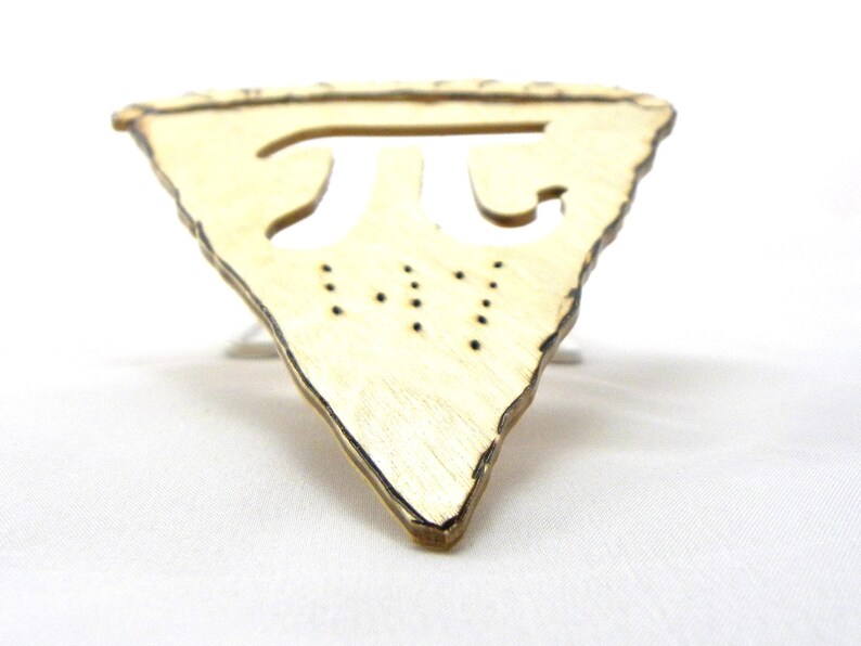 May include: A wooden pie-shaped ornament with a cutout of the mathematical symbol pi. The ornament is light brown and has a rough, rustic texture.