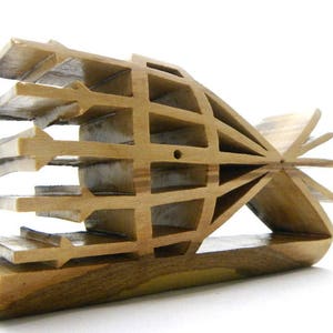 May include: A wooden sculpture with a geometric design. The sculpture is made of multiple pieces of wood that are joined together to create a complex pattern. The sculpture is brown in color and has a natural wood finish.