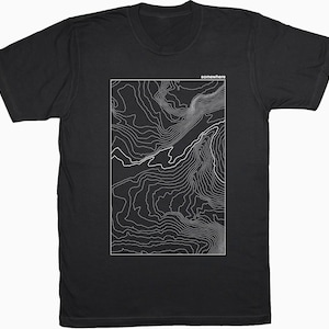 May include: A set of three ceramic mugs with a speckled, matte finish. The mugs are in shades of cream, light gray, and dark gray. Each mug has a simple, minimalist design and a rounded handle.