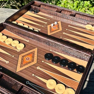 a backgammon game board with pieces and a wooden case, placed on a wooden surface.
