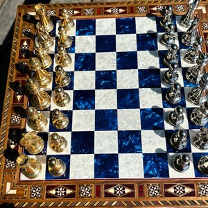 a chess board with a blue and white checkered pattern, and the pieces are made of metal.