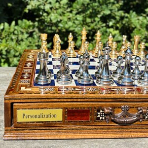 A wooden chess set with a blue and white checkered board, featuring a variety of chess pieces including knights, pawns, and other pieces.