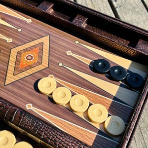 A game board with a wooden surface and a patterned design, featuring a game of checkers or backgammon pieces and a decorative element.
