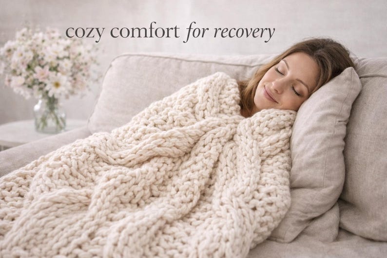 Puede incluir: Una persona descansa en un sof&aacute;, cubierta por una gruesa manta de punto color crema. La manta tiene un dise&ntilde;o de punto trenzado grueso. El texto "cozy comfort for recovery" est&aacute; en la parte superior de la imagen. Un jarr&oacute;n con flores est&aacute; en una mesa auxiliar.