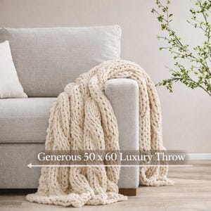 Chunky knit blanket draped over a neutral living room chair, luxury housewarming gift and welcome home gift for new homeowners
