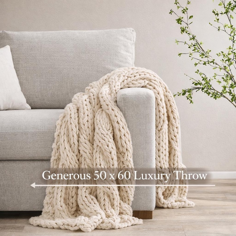 Chunky knit blanket draped over a neutral living room chair, luxury housewarming gift and welcome home gift for new homeowners