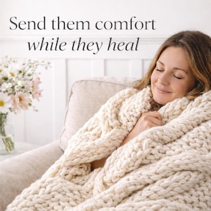 Puede incluir: Una mujer envuelta en una gruesa manta de punto color crema, sentada en un sof&aacute; beige. La manta tiene un dise&ntilde;o de punto trenzado. El texto de arriba dice "Env&iacute;ales consuelo mientras se curan". Un jarr&oacute;n con flores est&aacute; cerca.