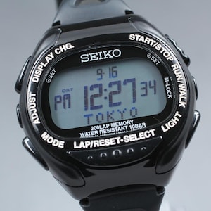 May include: Black Seiko digital watch with a rectangular display showing the date, time, and the word "TOKYO". The watch has multiple buttons and the text "300LAP MEMORY WATER RESISTANT 10BAR".