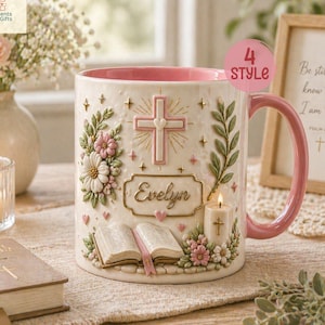 May include: A white ceramic mug with a pink interior and handle, decorated with a cross, flowers, and the name "Evelyn." The mug has a religious theme, with an open book and a lit candle. The text "4 STYLE" is also visible.