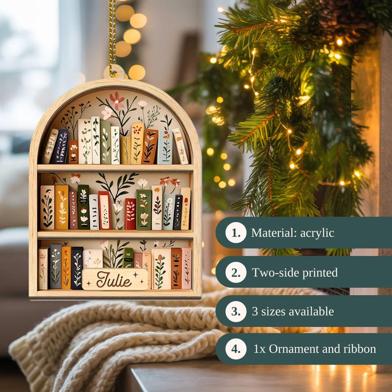 May include: Wooden bookshelf ornament with a floral design and the name "Julie". The two-sided printed ornament features miniature books on shelves. It is made of acrylic and includes a ribbon for hanging.