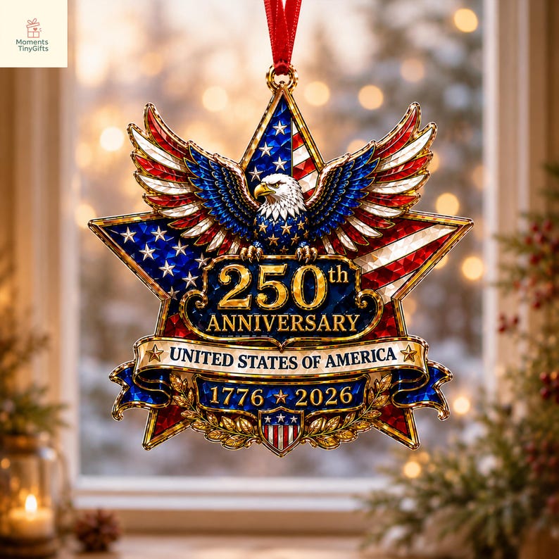 May include: A star-shaped commemorative ornament featuring a bald eagle with spread wings, the American flag, and gold text reading 250th ANNIVERSARY UNITED STATES OF AMERICA 1776-2026. The design includes a red ribbon hanger and gold metallic accents.
