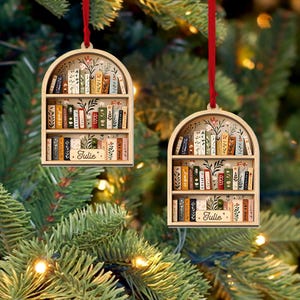 May include: Two wooden bookshelf ornaments with red ribbons for hanging. Each ornament features a miniature bookshelf filled with colorful books and floral accents. The name "Julie" is inscribed on a small wooden plaque on each shelf.