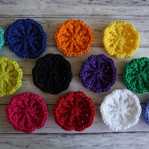 May include: Twelve crocheted round coasters in various colors, including teal, blue, orange, yellow, green, purple, black, red, white, and light blue.