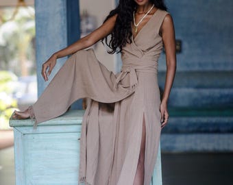 Peut inclure: Une robe portefeuille beige sans manches avec un décolleté en V, une taille nouée et une fente latérale haute avec des détails d'ourlet effilochés. La tenue comprend un chapeau fedora beige avec une bande à motifs et un collier simple.