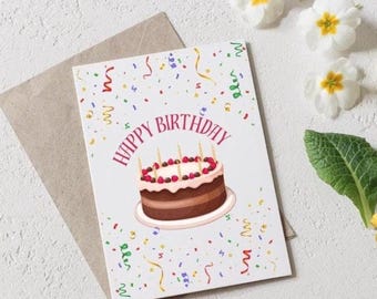 May include: A birthday greeting card with a chocolate cake illustration. The card features the words "Happy Birthday" in pink, with colorful confetti and streamers. The card is on a neutral envelope, with white flowers and greenery in the background.