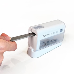May include: A white and clear plastic scalpel blade disposal unit with a stainless steel blade being inserted. The unit has the brand name "ensare" printed on the side. The text "made in korea" and a QR code are also visible.