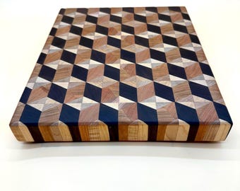 May include: A rectangular wooden cutting board with a geometric cube pattern. The design incorporates various wood tones, including light, medium, and dark browns, along with black accents. The board's edges are also made of wood.