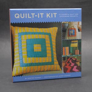 May include: A book cover for a quilting kit titled "Quilt-It Kit" with 15 colourful quilt and patchwork projects. The cover features a yellow and blue patchwork cushion with a square design.
