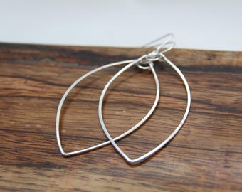 May include: A pair of silver earrings with a teardrop shape. The earrings are made of thin wire and have a delicate, minimalist design.