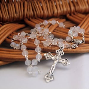 May include: A silver rosary with white moonstone beads and a silver crucifix.
