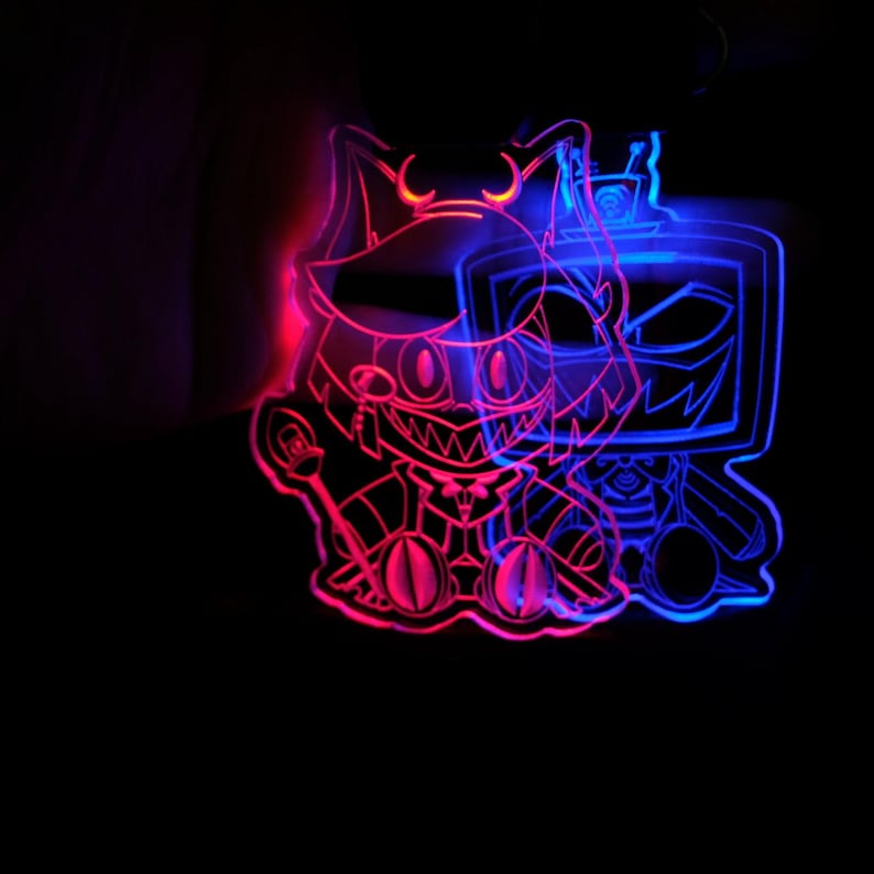 May include: A neon sign featuring two cartoon characters with a red and blue glow. The character on the left has cat-like ears and a mischievous grin, while the character on the right is a television with a sinister face. The sign is against a black background.