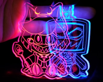 May include: A neon-lit keychain featuring two cartoon characters. One character is cat-like with a staff, the other is a TV head. The keychain glows with pink and blue light against a black background.