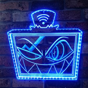May include: A blue LED light sign with a cartoon face design. The sign has a wifi symbol on top and a rectangular frame with a face design. The sign is mounted on a brick wall.