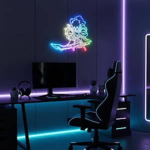 Puede incluir: Una configuración de juego con un escritorio, monitor y silla negros. Un letrero de neón colorido de un personaje de anime está montado en la pared. La habitación está iluminada con luces LED azules y moradas, creando un ambiente vibrante.