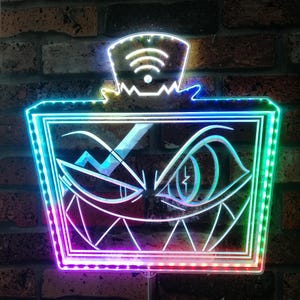 May include: A neon sign featuring a stylized face with sharp teeth and an eye with a lightning bolt. The sign has a Wi-Fi symbol on top and is outlined with a rainbow of colors, mounted on a brick wall.