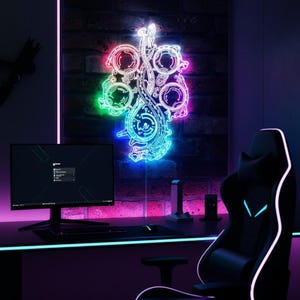 May include: A neon sign in a gaming room features a complex, glowing design with circular and geometric shapes, illuminated in vibrant colors. The room includes a black gaming chair, a computer monitor, and a desk with a keyboard and mouse.