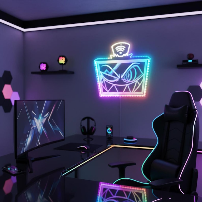 May include: A gaming room setup with a black desk, chair, and monitor. A neon sign with a face design is mounted on the wall. The room is illuminated with colorful LED lights, creating a vibrant atmosphere. Other accessories include headphones and a smartphone.