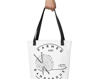 May include: White tote bag with black handles. The bag displays a black and white graphic of a ball of yarn and knitting needles, with the text "Yarned and Dangerous" in a circular design.
