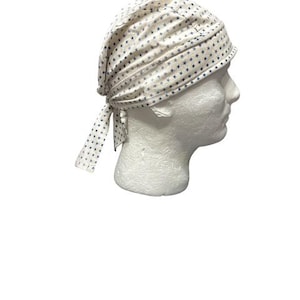 May include: A white head covering with a repeating pattern of small blue stars. The head covering is tied at the back with two long, narrow fabric strips. The head covering is shown on a white mannequin head.