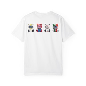 Può includere: T-shirt bianca con quattro illustrazioni di orsi colorati sul retro. Ogni orso ha un design unico con diversi colori e motivi, tra cui giallo, rosso, bianco e verde. Gli orsi hanno il testo "LIBERTY WALK" sul petto.
