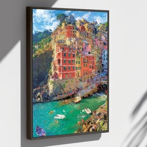 May include: A framed art print depicting a vibrant coastal village. The buildings are painted in shades of red, yellow, and orange, with a turquoise sea and blue sky. The artwork has a textured, impressionistic style.