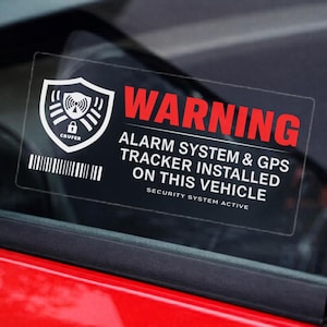 以下が含まれることがあります： 赤い「WARNING」の文字が入った、車の窓ガラスに貼られた透明なステッカー。「ALARM SYSTEM & GPS TRACKER INSTALLED ON THIS VEHICLE」と書かれており、セキュリティシールドのアイコンとバーコードが付いています。