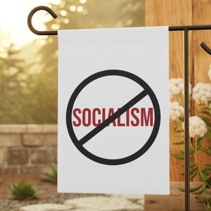 Könnte beinhalten: Eine weiße, rechteckige Gartenflagge mit einem schwarzen, kreisförmigen Verbotszeichen, das in der Mitte von einer diagonalen Linie durchkreuzt wird. Das Wort SOCIALISM ist in fetten, roten Großbuchstaben mittig aufgedruckt.