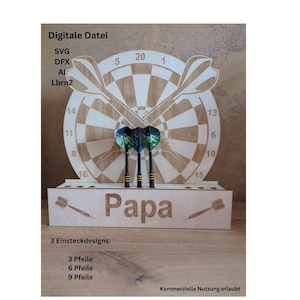 Może przedstawiać: Drewniana tarcza do darta z trzema lotkami, stojak z napisem "Papa" i tekstem "Digitale Datei". Tarcza do darta ma wzór tarczy z numerami. Stojak ma szczelinę na lotki. Obraz zawiera również tekst "3 Einsteckdesigns: 3 Pfeile, 6 Pfeile, 9 Pfeile".