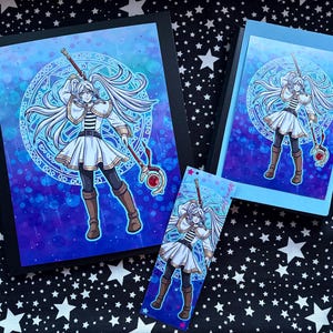 May include: A collection of fantasy art prints and a bookmark. Each item features a female character with long white hair, a white dress, and a staff. The background is a blue and purple gradient with a circular design. The items are on a star-patterned surface.