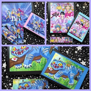 Op de afbeelding: Een verzameling ingelijste kunstafdrukken en kleinere afdrukken met kleurrijke illustraties in anime-stijl. De kunstwerken omvatten afbeeldingen van een groep vrouwelijke personages, mannelijke personages en een blauw tijgerachtig wezen. De prints worden gepresenteerd op een zwart-witte sterrenachtergrond.