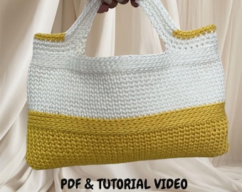 May include: A white and yellow crochet tote bag. The bag has a rectangular shape with a white body and a yellow base. The handles and top trim are white. The text "PDF & TUTORIAL VIDEO" is visible at the bottom of the image.
