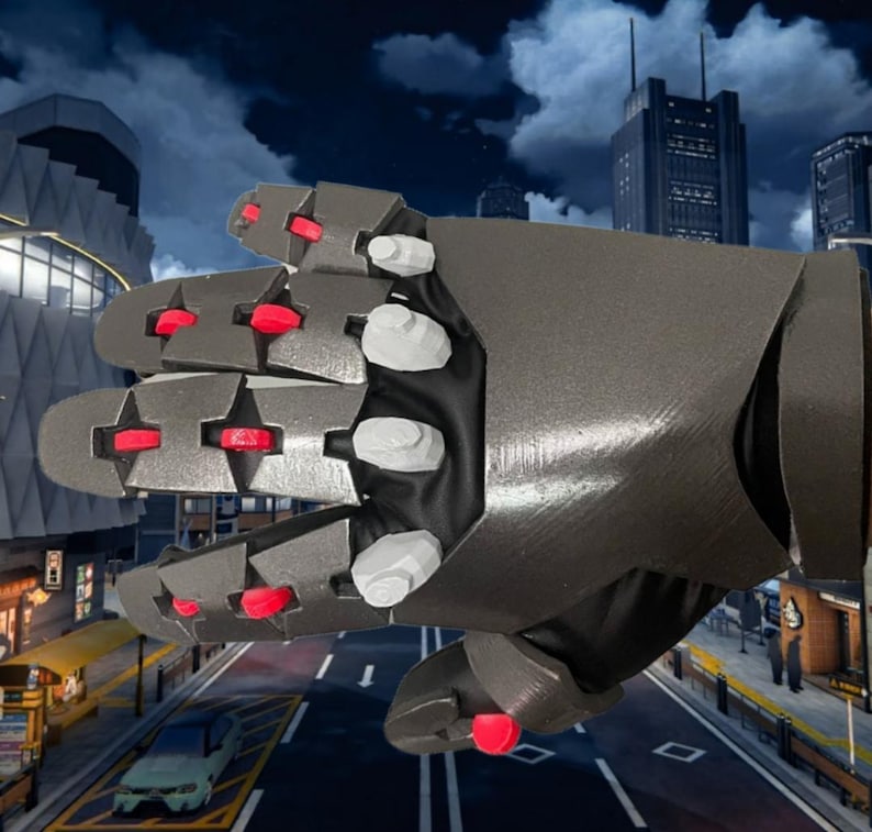 May include: A metallic gray robotic hand with red and white accents. The fingers and palm are articulated, with red circular details at the joints. The background features a cityscape with buildings and a street.