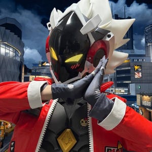 May include: A futuristic cosplay costume featuring a black and red helmet with yellow glowing eyes. The costume includes a red jacket with white trim, a gray and black body suit, and black gloves. The background shows a cityscape.