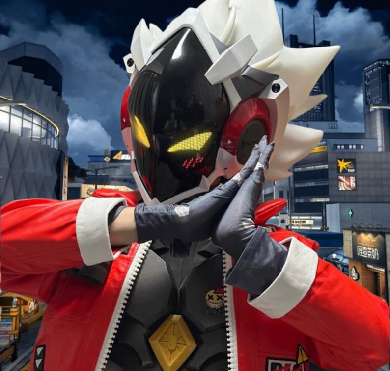 May include: A futuristic cosplay costume featuring a black and red helmet with yellow glowing eyes. The costume includes a red jacket with white trim, a gray and black body suit, and black gloves. The background shows a cityscape.